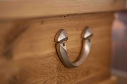 Détail d'une poignée de cercueil en bois exposé en agence