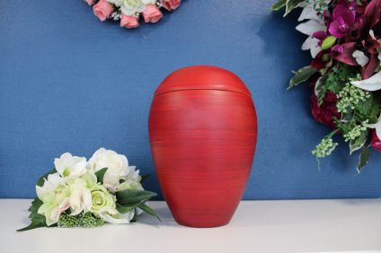Urne funéraire rouge présentée avec des fleurs